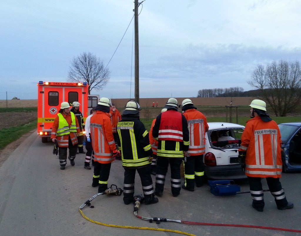 Einsatzkräfte umstellen ein Unfallfahrzeug an einem Straßenrand.